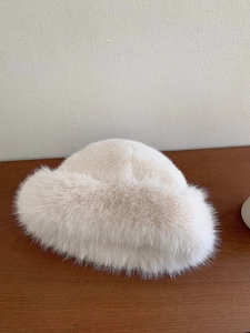 Macro detail showing the soft texture and fluffy faux fur fibers of the beige bucket hat