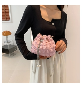 Detail of pink pleated bucket bag with metal chain strap and pearl charm pendant