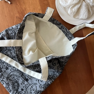 Detail view of cotton linen tote bag with paisley pattern and white canvas handle on wood