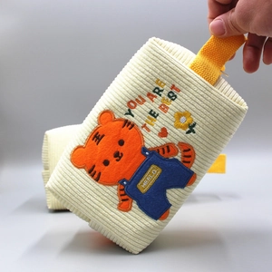 Detail der cremefarbenen Cord-Tasche mit Tiger-Stickerei und gelbem Tragegriff