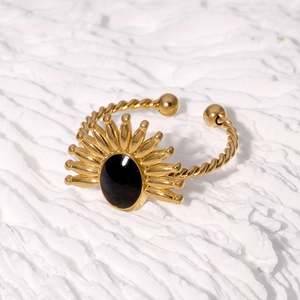 Vue détaillée de la bague en acier doré avec pierre noire ovale et motif de rayons