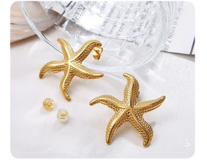 Macro shot of 18K gold plated starfish earrings with textured surface and clear backs