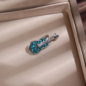 Vue macro d'une broche guitare musicale avec des strass verts incrustés sur métal