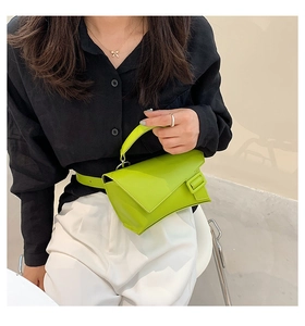 Detail of neon green leather waist bag with square buckle on a model wearing black and white