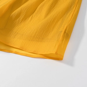 Close-up of yellow ruffled hem and wrinkled chiffon fabric texture on a two-piece set
