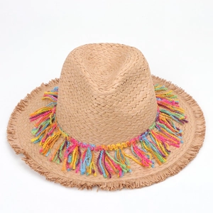 Detail of bohemian straw hat with colorful cotton tassels and stylish frayed edge brim