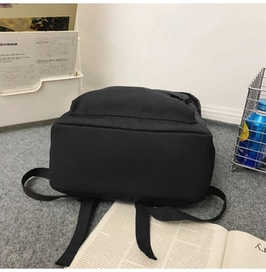 Close-up of black water-resistant nylon backpack with front pocket on a grey rug