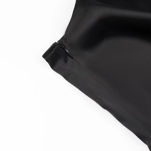 Gros plan d'une fermeture éclair invisible sur une robe noire en satin au tissu lisse