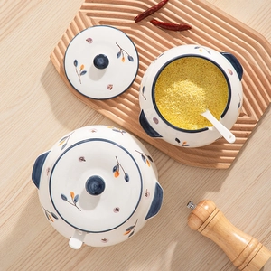 Japanese ceramic seasoning jars with hand-painted floral patterns and lids on wood