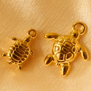 Gold stainless steel sea turtle charms for DIY jewelry on elegant golden silk fabric