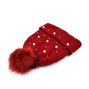Dettaglio berretto in maglia rosso scuro con perle e pompon in pelliccia