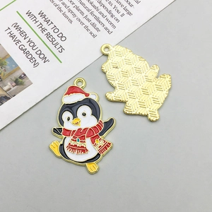 Detail of Christmas penguin enamel charms with festive red hat and gold metal backing