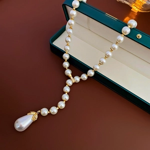Detail of a vintage pearl teardrop necklace with gold chain in a green jewelry box