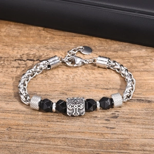 Close-up of black faceted beads and vintage cross charm on a mixed metal bracelet