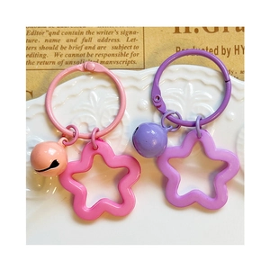 Colorful star acrylic keychains with bells in pink and purple on a ceramic plate