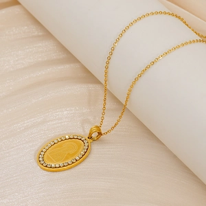 Detail of a gold oval Virgin Mary pendant with sparkling rhinestones on an O-chain