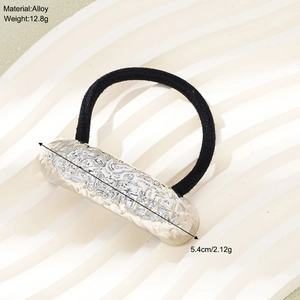 Detail of silver alloy ponytail holder showing 5.4cm metal bar with hammered texture