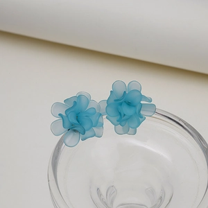 Macro view of sky blue matte translucent floral earrings on a glass edge