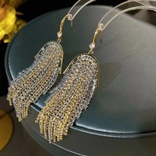 Close-up of elegant gold tassel earrings with shimmering crystals on a jewelry stand