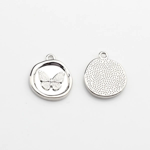 Detailed macro view of silver alloy round pendants with embossed butterfly motif and textures