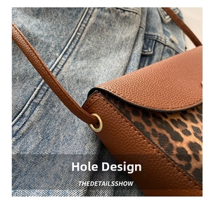 Macro detail of the perforated eyelet design on a brown pebbled leather leopard saddle bag