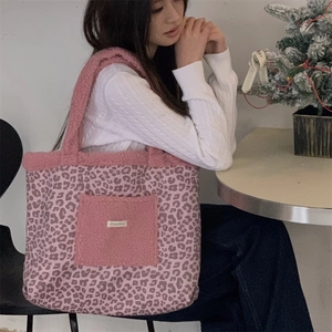 Pink leopard print plush tote bag with solid pink front pocket shown on a shoulder