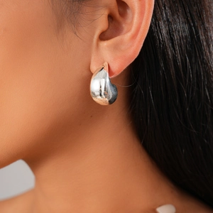 Close-up of polished silver teardrop earring worn by a model with soft lighting