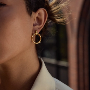 Luxe textured gold stainless steel hoop earrings with multi-color gemstones on a model