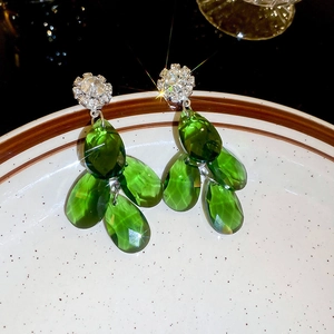 Detailed macro of vintage emerald green teardrop earrings in a white ceramic dish