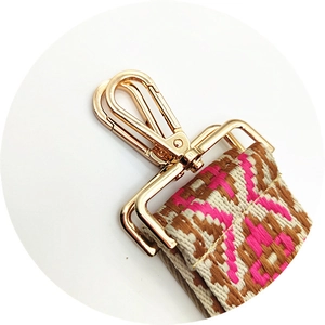 Close-up of ethnic style woven bag strap with golden lobster clasp and geometric pattern