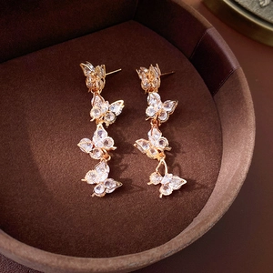 Detail of gold butterfly long tassel earrings with sparkling white zircons in a box