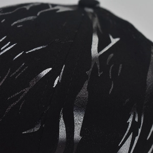 Detail of black twill baseball cap showing silver metallic abstract flame print