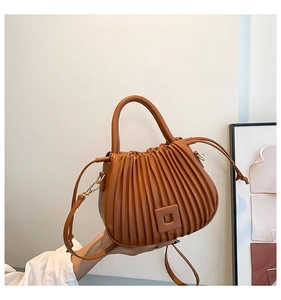 Detail of pleated brown faux leather bucket bag with square buckle and gold hardware