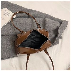 Macro shot of brown patent leather bag interior with silver zipper and spacious black lining