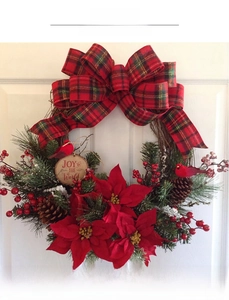 Close-up of Christmas wreath with red berries, poinsettia, and Joy to the World wooden sign