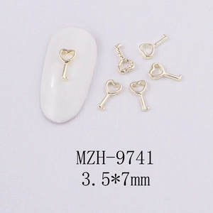 Détail macro de breloques à ongles clés dorées en forme de cœur pour manucure DIY
