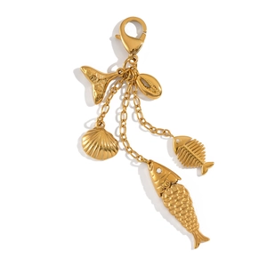 Detailed macro of gold ocean-themed charms with fishbone and shell on lobster clasp