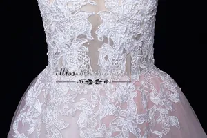Détail d'une robe de mariée rose avec dentelle florale blanche et tissu en maille