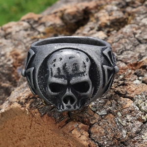 Vintage stainless steel skull ring with dark gothic aesthetic on a natural wood background