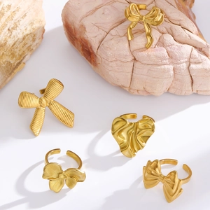 Detail of five gold bow and heart rings with textured metal and adjustable bands