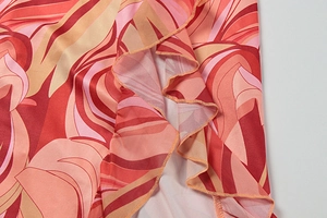 Detail of ruffled hem with vibrant abstract leaf print on a slim summer dress
