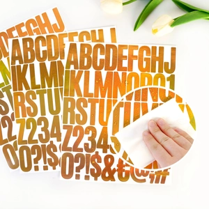 Close-up of waterproof gold metallic alphabet stickers being wiped clean with a cloth