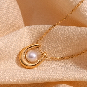 Detail shot of 18K gold U-shaped pendant with a white pearl on satin silk