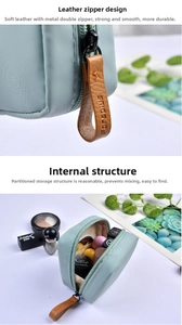 Detail view of light green lipstick pouch with leather zipper pull and internal pockets