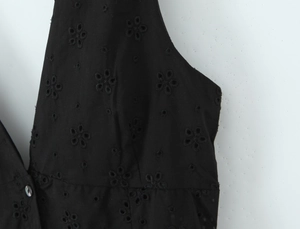 Détail de la robe noire en coton avec broderie florale ajourée et fermeture à boutons