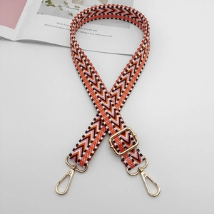 Detail of adjustable woven shoulder strap with geometric chevron pattern and gold lobster claws
