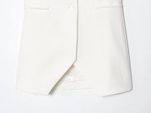 Détail du gilet blanc avec fermeture à bouton et ourlet croisé asymétrique élégant