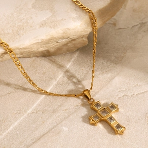 Detailed macro view of a gold cross pendant with sparkling square zircon stone inlays