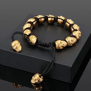 Detailed shot of punk skull bracelet with gold metal charms and black braided rope