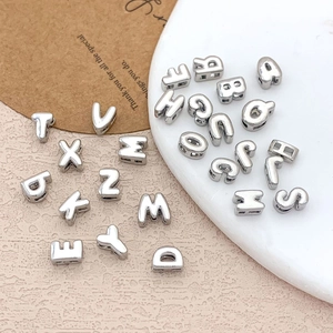 Polished silver alphabet beads with side holes for DIY jewelry making on textured background